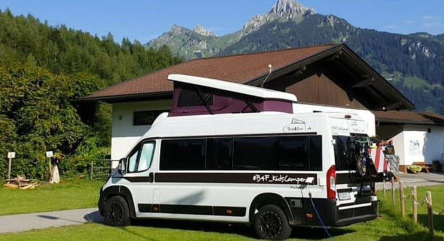 Der Fiat Ducato Familiencamper mit hochgeklapptem Aufstelldach vor Bergkulisse in Österreich